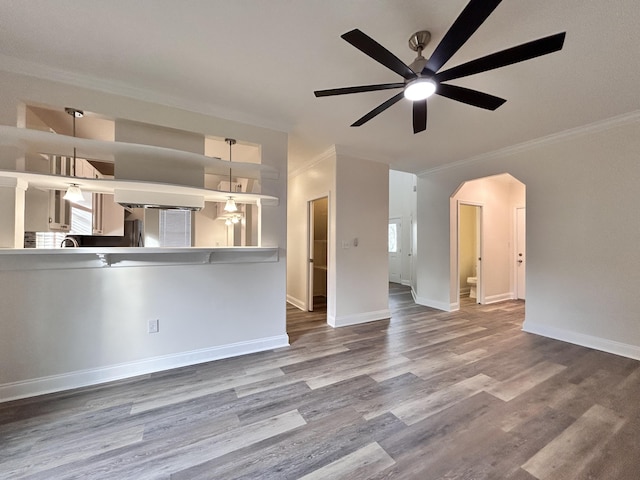 unfurnished living room with wood-type flooring, ornamental molding, and ceiling fan