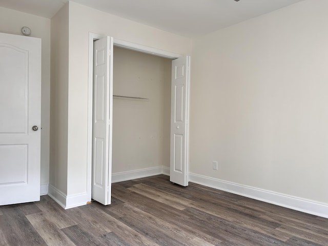 unfurnished bedroom with dark hardwood / wood-style flooring and a closet