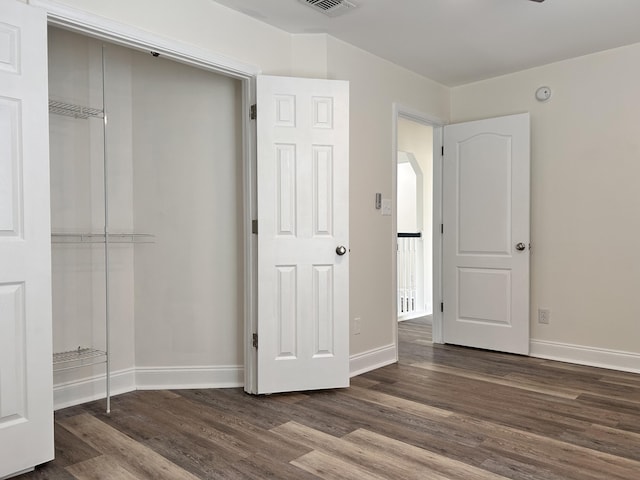 unfurnished bedroom with dark hardwood / wood-style flooring and a closet