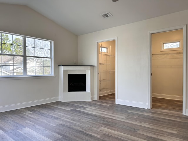 unfurnished living room with lofted ceiling, a healthy amount of sunlight, a fireplace, and wood-type flooring