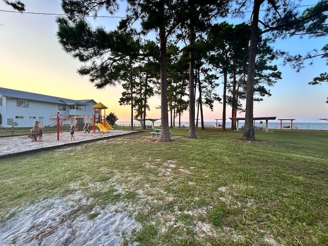 yard at dusk featuring a water view and a playground