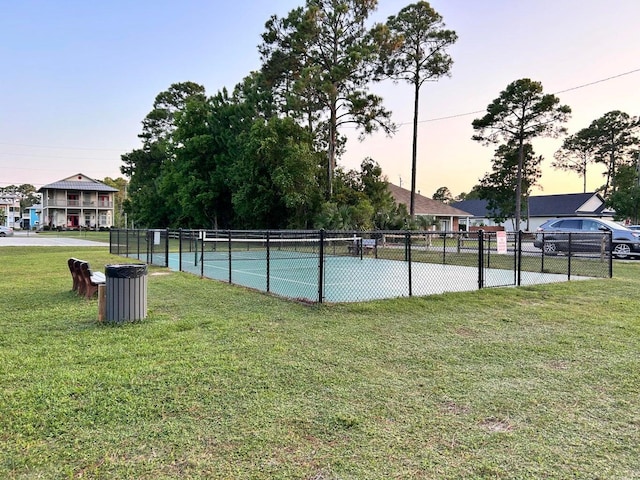 pool at dusk with a yard and tennis court