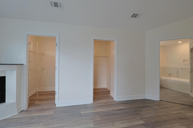 149 Legion Park Loop, Miramar Beach, FL 32550 - unfurnished bedroom featuring a walk in closet, a closet, a tile fireplace, wood finished floors, and connected bathroom