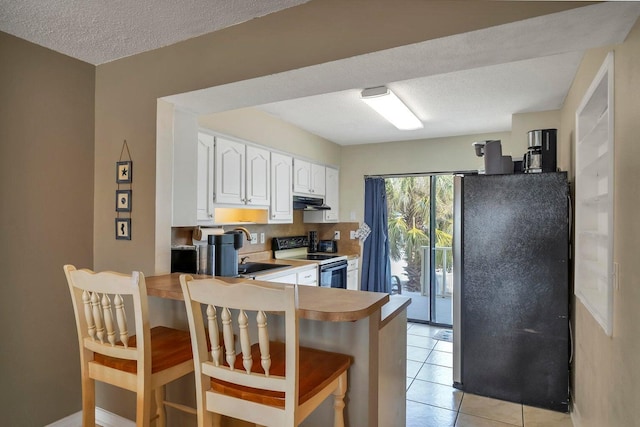 8468 Gulf Blvd # Ut-4, Navarre, FL 32566 - kitchen featuring a breakfast bar, sink, white cabinets, stainless steel fridge, and electric stove