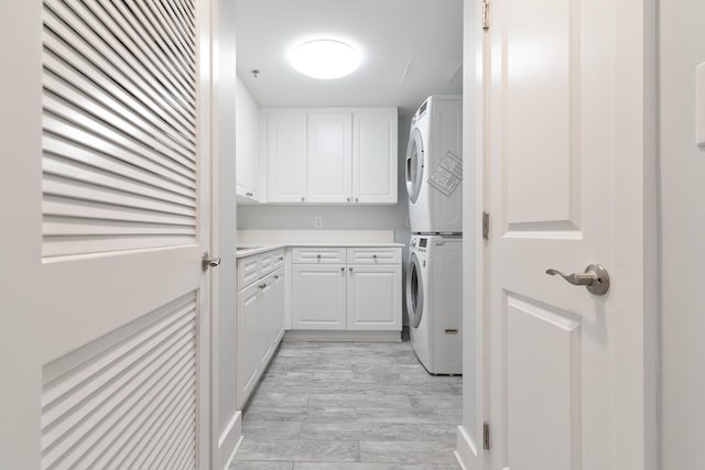 laundry area featuring cabinets, stacked washer and clothes dryer, and light hardwood / wood-style floors