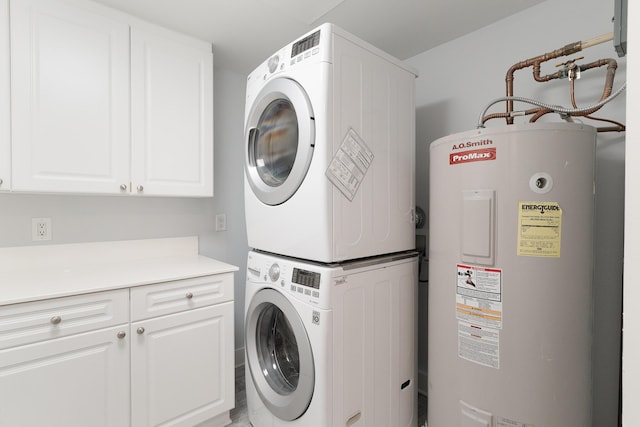 laundry room featuring water heater, stacked washer and dryer, and cabinets