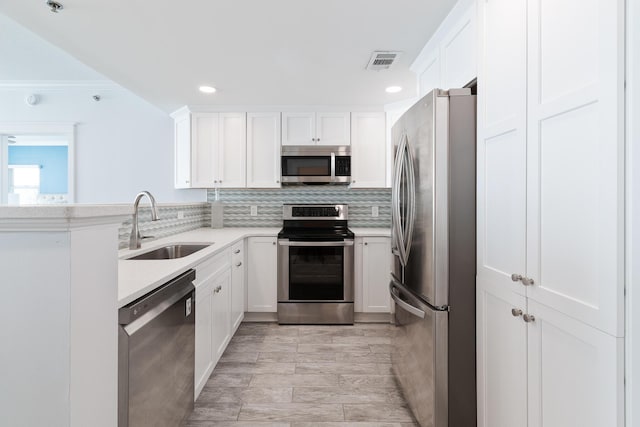 kitchen featuring stainless steel appliances, sink, white cabinets, and backsplash