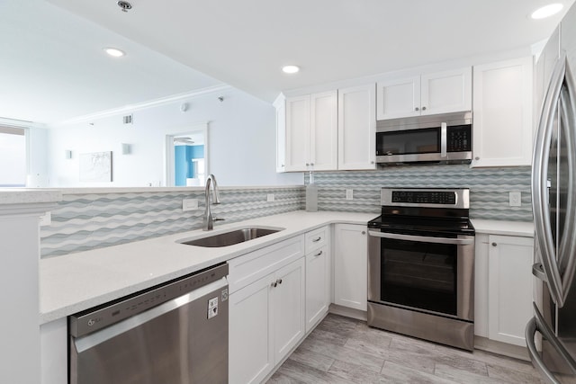 kitchen with stainless steel appliances, sink, white cabinets, and backsplash