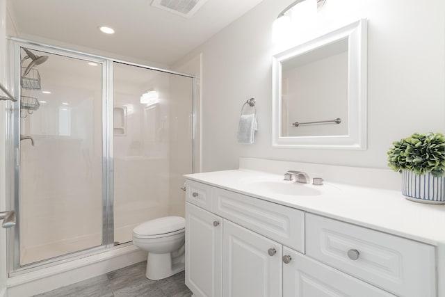 bathroom with an enclosed shower, vanity, hardwood / wood-style flooring, and toilet