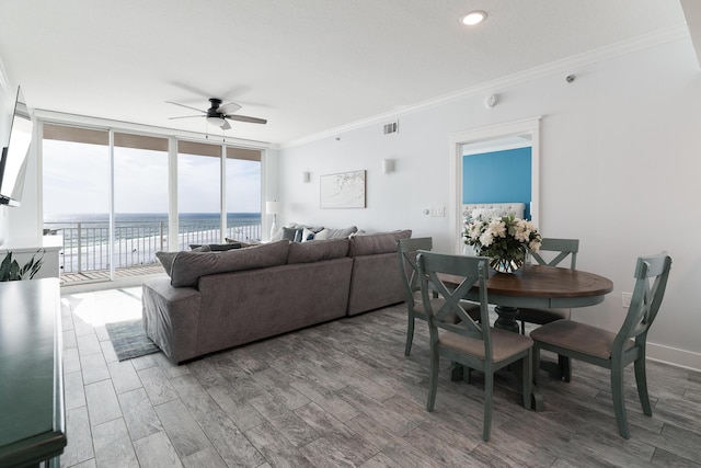 living room with a wall of windows, hardwood / wood-style flooring, ornamental molding, ceiling fan, and a water view