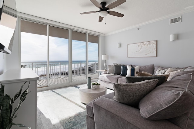 living room with a wall of windows, ceiling fan, a water view, ornamental molding, and light wood-type flooring