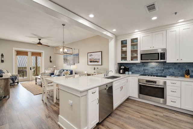 kitchen featuring visible vents, decorative backsplash, open floor plan, a peninsula, and stainless steel appliances