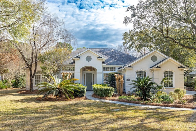 mediterranean / spanish house featuring brick siding and a front lawn