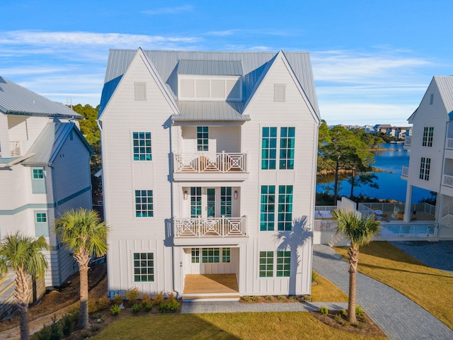 view of front facade with a front lawn, a balcony, and a water view