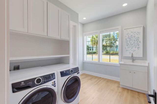 washroom with cabinets, sink, washing machine and dryer, and light wood-type flooring