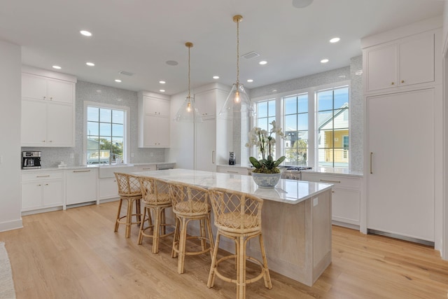 kitchen featuring light stone counters, light hardwood / wood-style flooring, a center island, and white cabinets