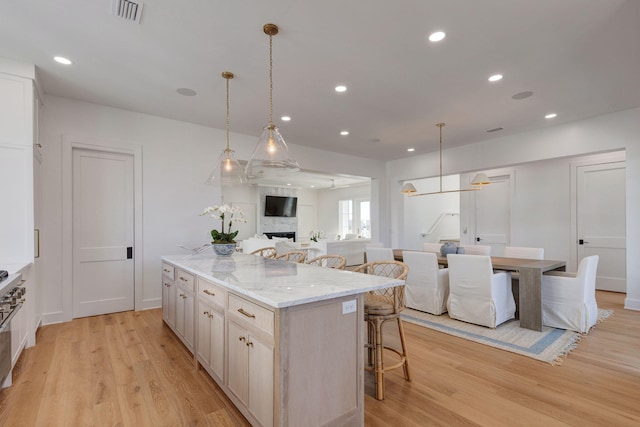 kitchen with hanging light fixtures, a large island, a breakfast bar area, and light hardwood / wood-style floors