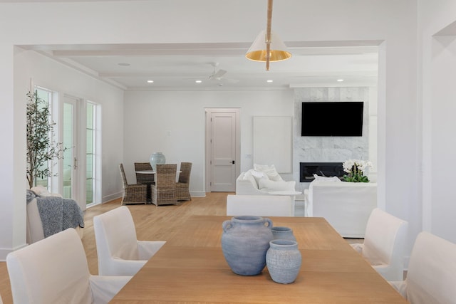 dining room featuring beamed ceiling, a premium fireplace, and light wood-type flooring