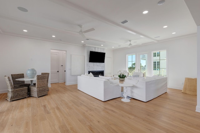 living room with crown molding, ceiling fan, a fireplace, light hardwood / wood-style floors, and beamed ceiling