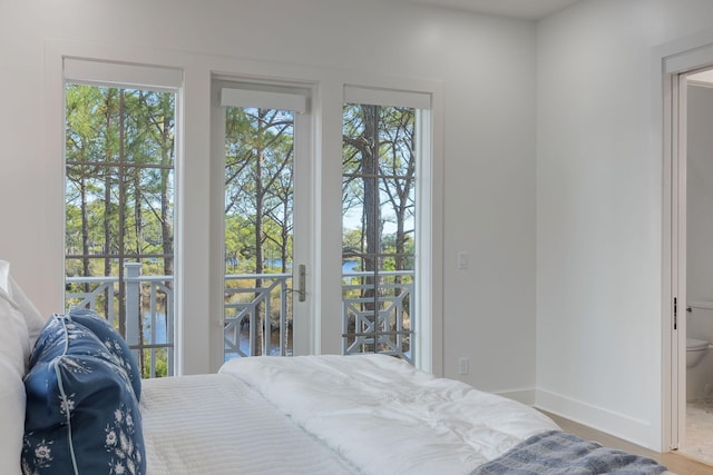 bedroom featuring a water view, access to exterior, and ensuite bath