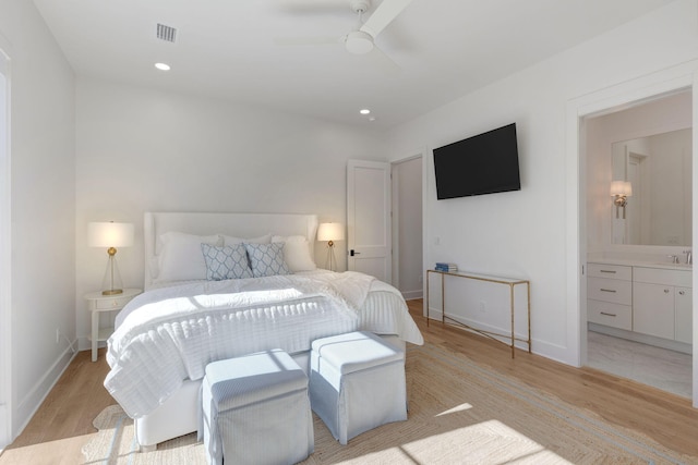 bedroom featuring ceiling fan, sink, ensuite bath, and light hardwood / wood-style flooring