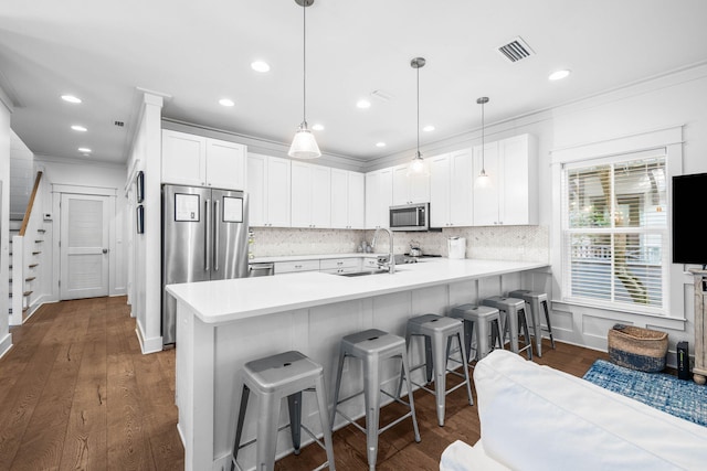 kitchen featuring white cabinets, pendant lighting, appliances with stainless steel finishes, and kitchen peninsula