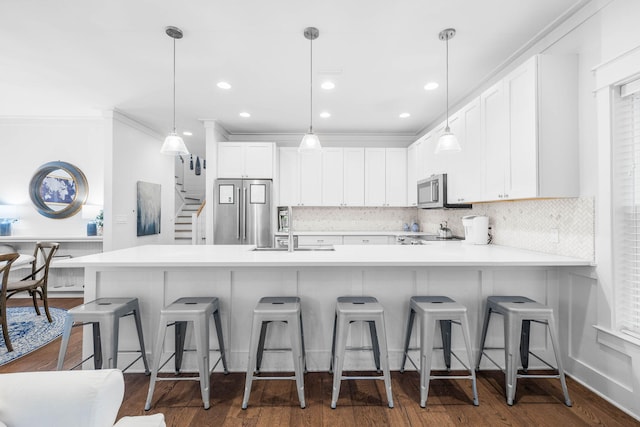 kitchen featuring white cabinetry, appliances with stainless steel finishes, sink, and hanging light fixtures