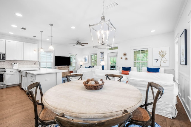 dining space with light hardwood / wood-style floors, a wealth of natural light, crown molding, and sink