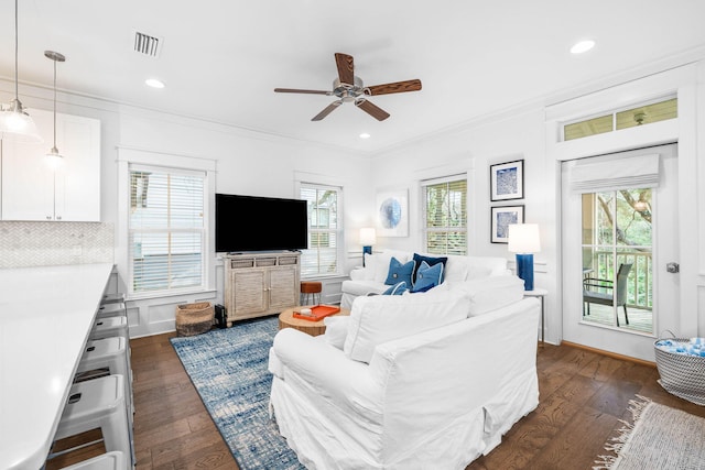 living room with crown molding, dark hardwood / wood-style flooring, and ceiling fan