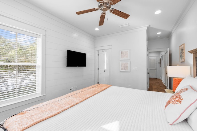 bedroom with ceiling fan, wood walls, and ornamental molding