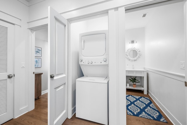 laundry area featuring sink, stacked washer / dryer, and dark hardwood / wood-style floors