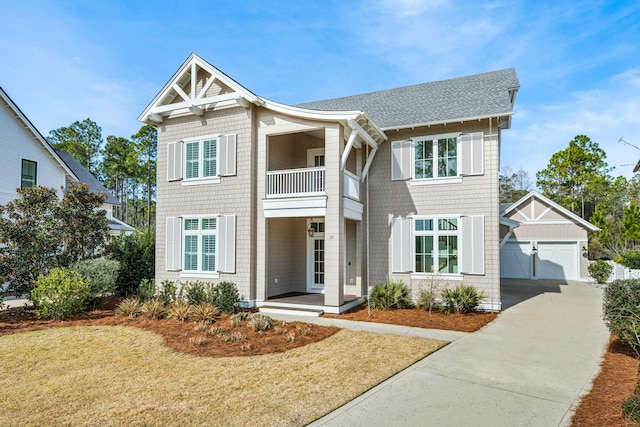 craftsman-style house featuring a garage, a shingled roof, an outdoor structure, and a front yard