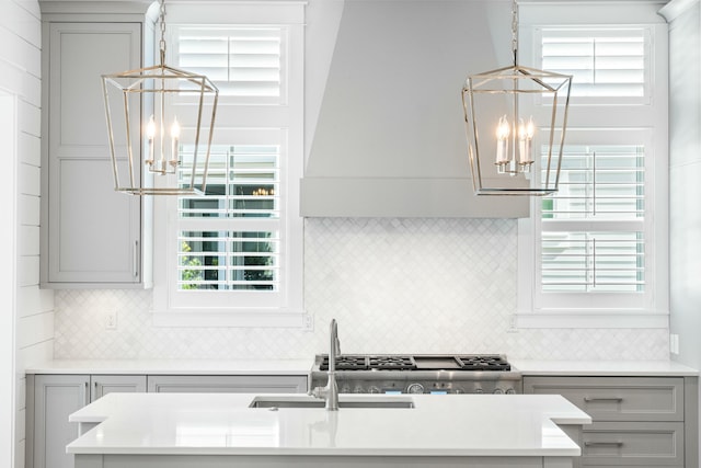 kitchen featuring gray cabinetry, light countertops, decorative backsplash, and an inviting chandelier