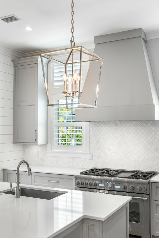 kitchen with light countertops, gray cabinets, a sink, and stainless steel stove