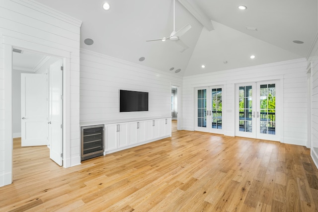 unfurnished living room with light wood-style floors, beverage cooler, high vaulted ceiling, and french doors