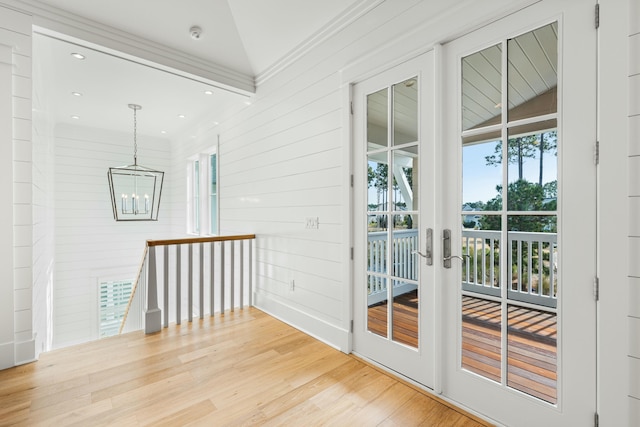 interior space with ornamental molding, vaulted ceiling, french doors, light wood-type flooring, and a chandelier