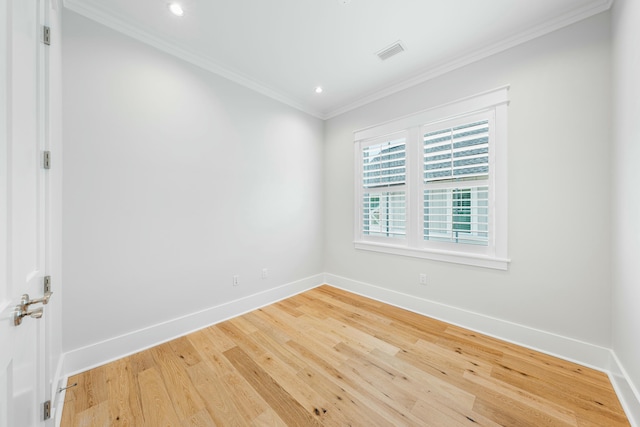 spare room with baseboards, wood finished floors, visible vents, and crown molding