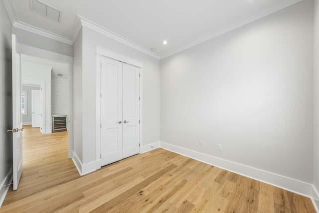 unfurnished bedroom featuring crown molding, light hardwood / wood-style floors, and a closet