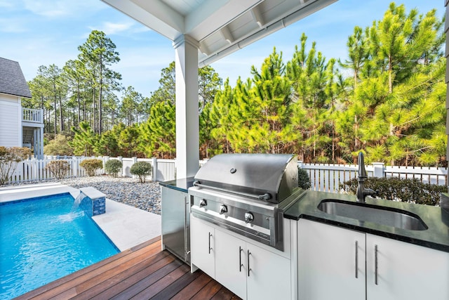 exterior space with sink, a pool side deck, a grill, pool water feature, and an outdoor kitchen