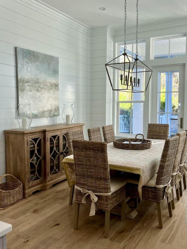 dining area featuring light wood finished floors, ornamental molding, and a notable chandelier