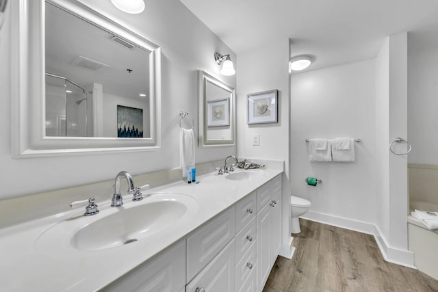 bathroom featuring hardwood / wood-style flooring, vanity, a shower with door, and toilet