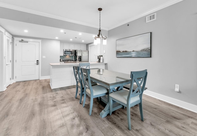 dining room with light hardwood / wood-style flooring and ornamental molding