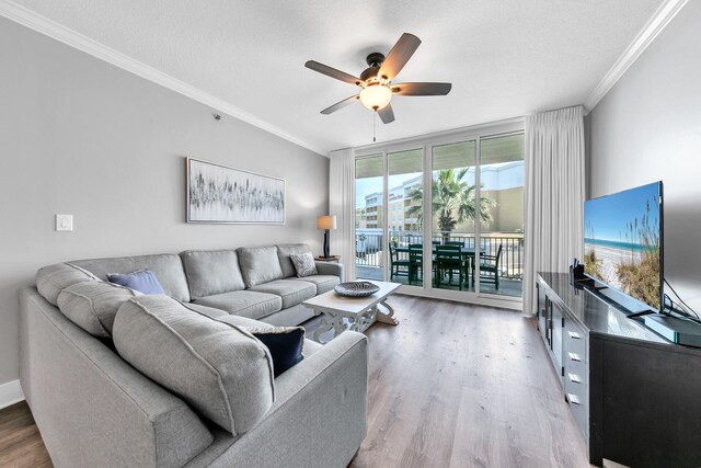 living room featuring ceiling fan, hardwood / wood-style floors, floor to ceiling windows, ornamental molding, and a textured ceiling