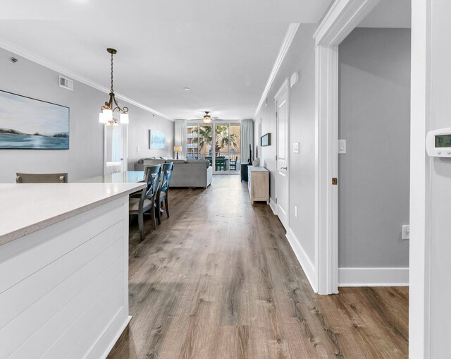 hall with crown molding, wood-type flooring, and a notable chandelier