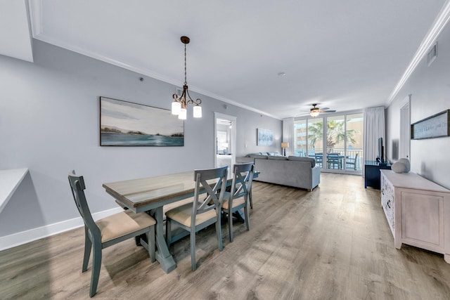 dining space with expansive windows, ornamental molding, ceiling fan with notable chandelier, and light hardwood / wood-style flooring