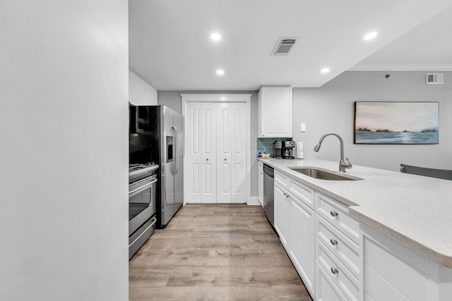 kitchen with sink, white cabinetry, crown molding, stainless steel appliances, and light hardwood / wood-style floors