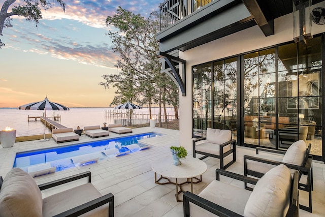 view of patio with a fenced in pool, a water view, an outdoor hangout area, fence, and a balcony