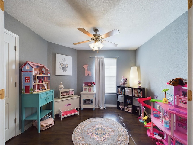 playroom featuring a textured ceiling, a textured wall, wood finished floors, and a ceiling fan