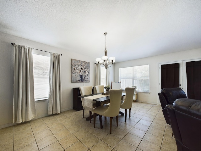 dining area with a notable chandelier, a textured ceiling, baseboards, and light tile patterned floors