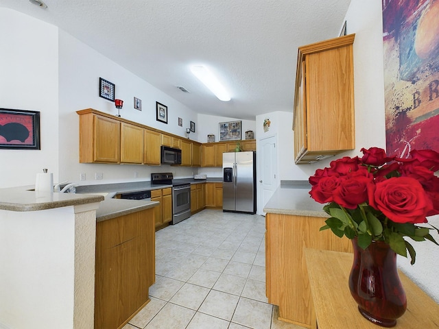 kitchen with a textured ceiling, light tile patterned floors, visible vents, appliances with stainless steel finishes, and brown cabinets